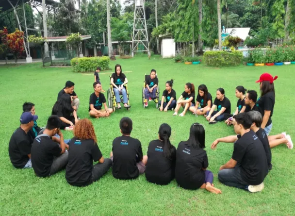 Virtualahan coaches and students sitting on the ground forming a circle during one of their wellbeing sessions.