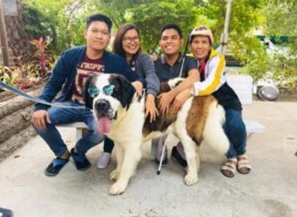 A picture of Jorim Pagaran with his 3 other persons sitting on a bench with a dog in front of them.