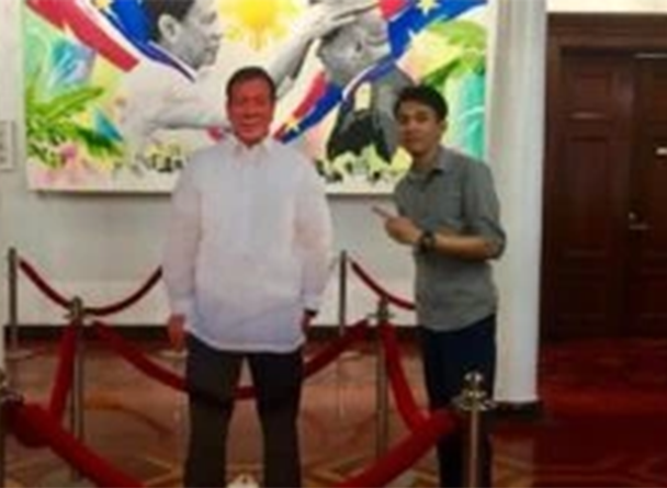 Jerico Canlas standing beside a standee of President Duterte